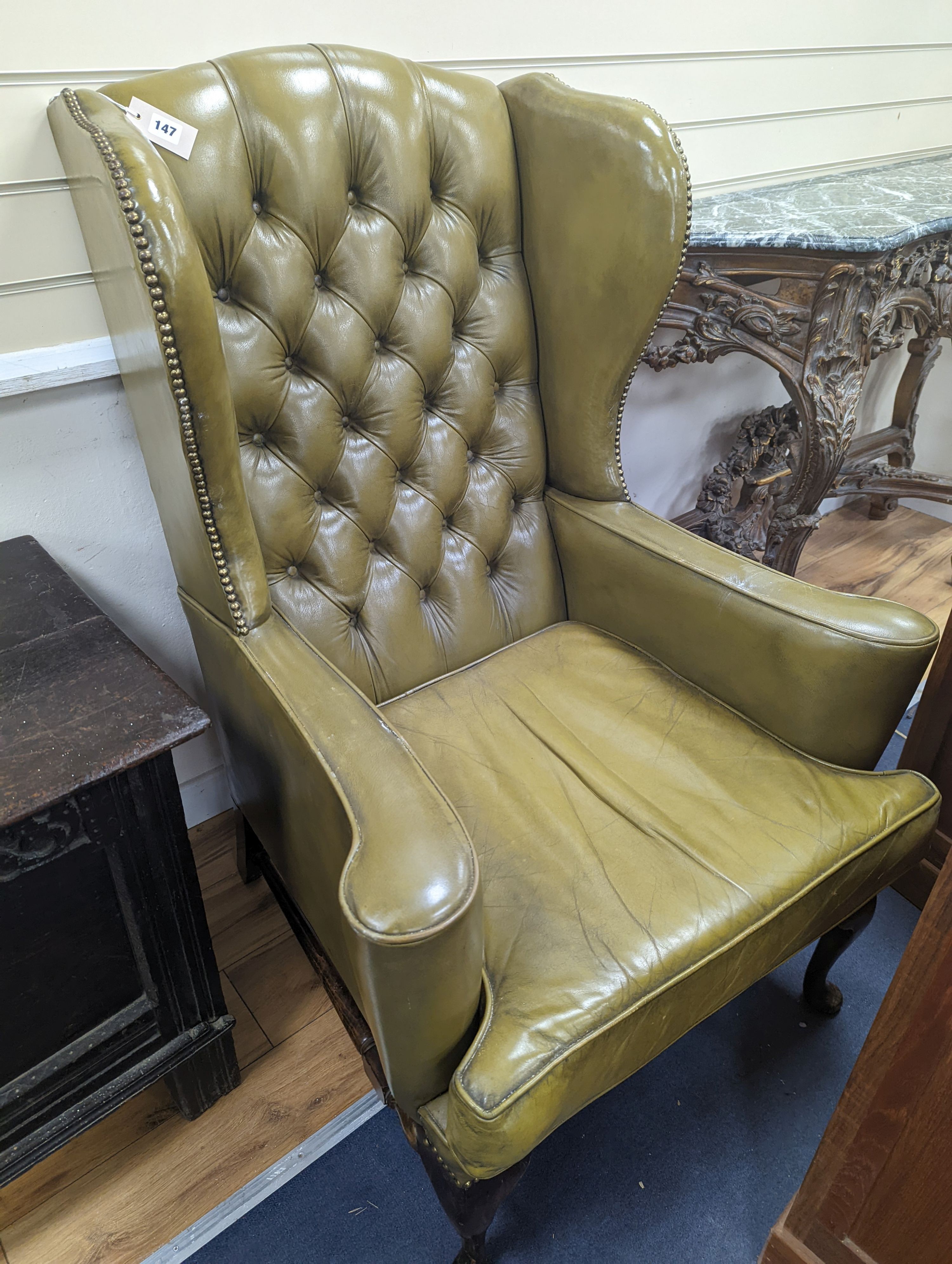 A George III style wing armchair upholstered in studded buttoned green leather, width 79cm, depth 76cm, height 116cm